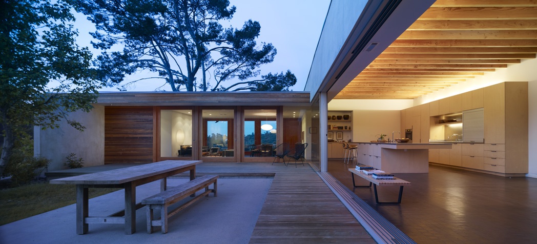 The concept connecting interior living area to exterior courtyard is a transparency delivered via custom pivot doors. For the kitchen/family room area, the architects used sliding aluminum doors.
